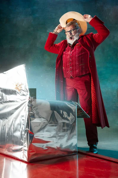 ซานตาคลอสสไตล์โมเดิร์นในชุดแฟชั่นสีแดงและหมวกคาวบอยบนพื้นหลังที่มืด — ภาพถ่ายสต็อก