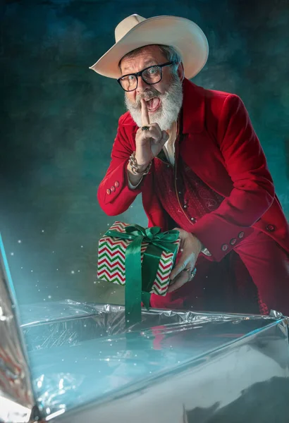 Moderno Papai Noel elegante em terno elegante vermelho e chapéu de cowboys no fundo escuro — Fotografia de Stock