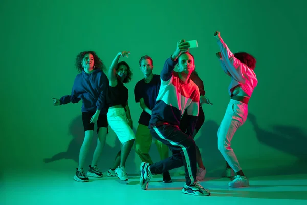 Stílusos férfiak és nők táncolnak hip-hop fényes ruhákban gradiens háttér táncterem neon fény — Stock Fotó
