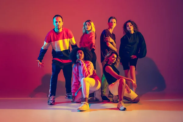 Hombres y mujeres con estilo bailando hip-hop en ropa brillante sobre fondo degradado en la sala de baile en luz de neón —  Fotos de Stock