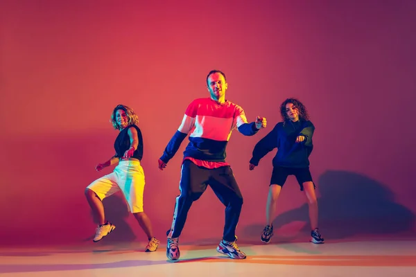 Hombre y mujeres con estilo bailando hip-hop en ropa brillante sobre fondo degradado en la sala de baile en luz de neón —  Fotos de Stock