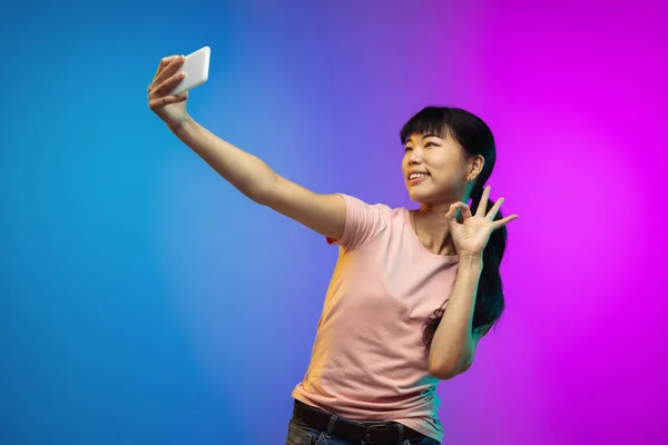 Asijské mladé ženy portrét na gradient studio pozadí v neonu — Stock fotografie