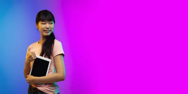 Asian young womans portrait on gradient studio background in neon