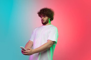 Beyaz tenli genç adam, neon renkli gradyan stüdyo arka planında portre çiziyor.