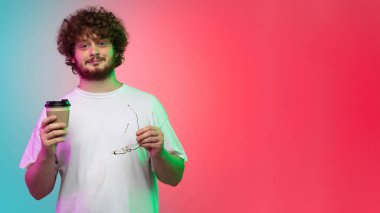 Beyaz tenli genç adam, neon renkli gradyan stüdyo arka planında portre çiziyor.