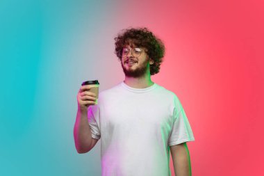 Beyaz tenli genç adam, neon renkli gradyan stüdyo arka planında portre çiziyor.