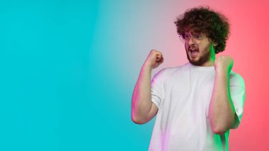 Beyaz tenli genç adam, neon renkli gradyan stüdyo arka planında portre çiziyor.