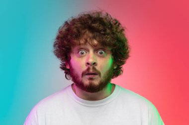 Beyaz tenli genç adam, neon renkli gradyan stüdyo arka planında portre çiziyor.