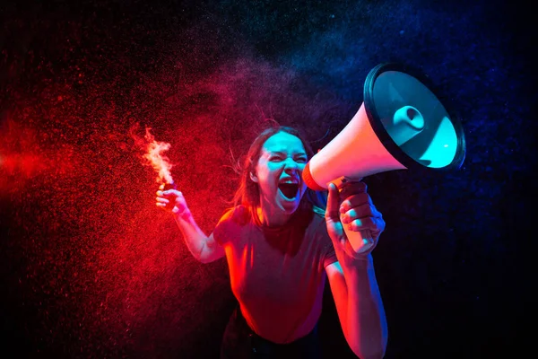 Skrik med megafon. ung kvinna med rök och neonljus på svart bakgrund. Mycket spänd, vidvinkel, fiskögon — Stockfoto