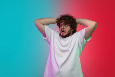 Beyaz tenli genç adam, neon renkli gradyan stüdyo arka planında portre çiziyor.