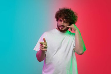 Beyaz tenli genç adam, neon renkli gradyan stüdyo arka planında portre çiziyor.