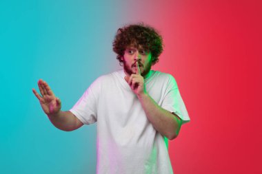 Beyaz tenli genç adam, neon renkli gradyan stüdyo arka planında portre çiziyor.