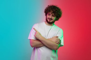 Beyaz tenli genç adam, neon renkli gradyan stüdyo arka planında portre çiziyor.