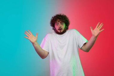 Beyaz tenli genç adam, neon renkli gradyan stüdyo arka planında portre çiziyor.