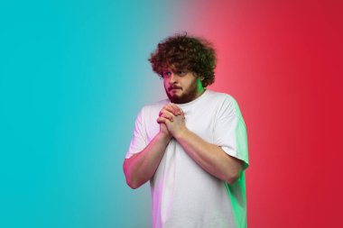 Beyaz tenli genç adam, neon renkli gradyan stüdyo arka planında portre çiziyor.