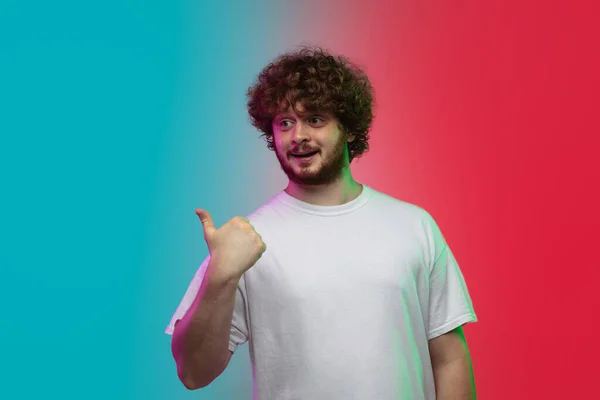 Beyaz tenli genç adam, neon renkli gradyan stüdyo arka planında portre çiziyor. — Stok fotoğraf
