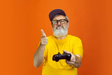 Kıdemli hippi cihazlar kullanıyor, turuncu arka planda aletler. Teknolojik ve neşeli yaşlı yaşam tarzı konsepti