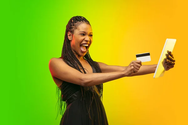 Retrato de mujer joven en luz de neón sobre fondo degradado. Las emociones humanas, viernes negro, lunes cibernético, compras, ventas, concepto de finanzas. —  Fotos de Stock