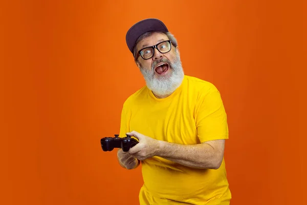Hombre hipster senior usando dispositivos, artilugios sobre fondo naranja. Tecnología y alegre concepto de estilo de vida de ancianos — Foto de Stock