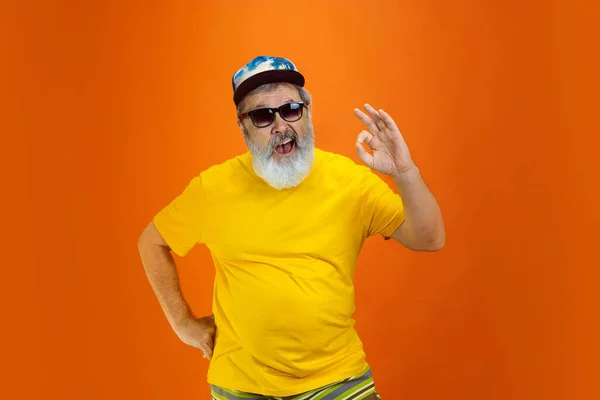 Hombre hipster senior con anteojos posando sobre fondo naranja. Tecnología y alegre concepto de estilo de vida de ancianos — Foto de Stock