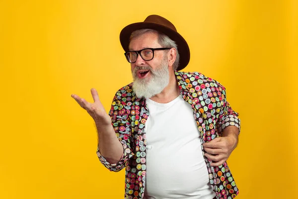 Homem hipster sênior usando óculos posando no fundo amarelo. Conceito de tecnologia e estilo de vida idoso alegre — Fotografia de Stock