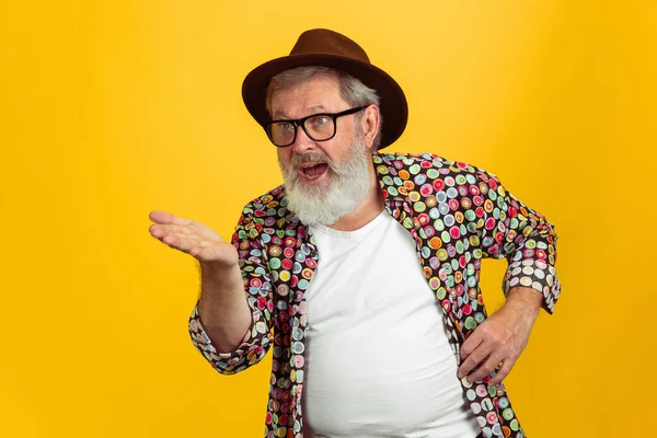 Hombre hipster senior con anteojos posando sobre fondo amarillo. Tecnología y alegre concepto de estilo de vida de ancianos — Foto de Stock