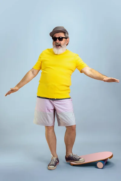 Starší hipster muž s brýlemi pózující na světle modrém pozadí. Technický a radostný životní styl seniorů — Stock fotografie