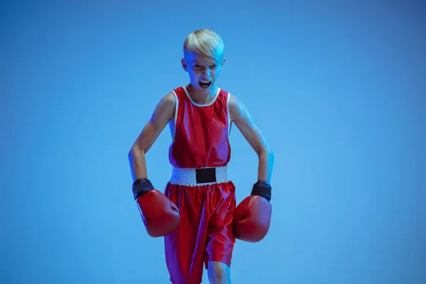 Adolescente en el boxeo de ropa deportiva aislado en fondo de estudio azul en luz de neón — Foto de Stock