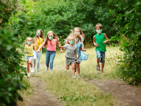 Felices niños caucásicos saltando y corriendo en el prado, en el bosque —  Fotos de Stock