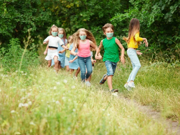 Felices niños caucásicos saltando y corriendo en el prado, en el bosque —  Fotos de Stock