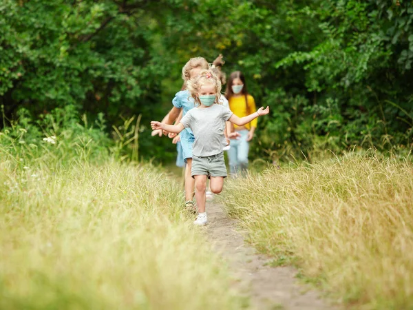 Felices niños caucásicos saltando y corriendo en el prado, en el bosque —  Fotos de Stock