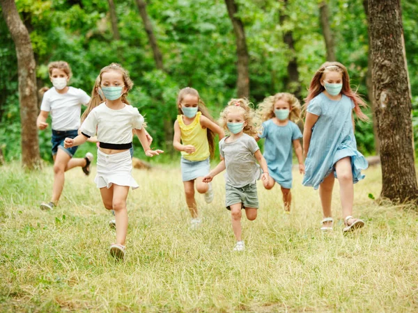Crianças caucasianas felizes pulando e correndo no prado, na floresta — Fotografia de Stock