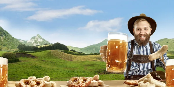 El hombre sonriente feliz con cerveza vestida con traje tradicional austriaco o bávaro sosteniendo taza de cerveza, montañas en el fondo, volante —  Fotos de Stock