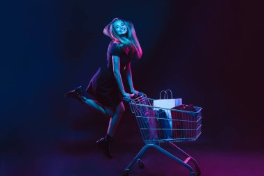 Karanlık arka planda neon ışıklı genç bir kadının portresi. İnsan duyguları, Kara Cuma, siber pazartesi, alışverişler, satışlar, finans konsepti.