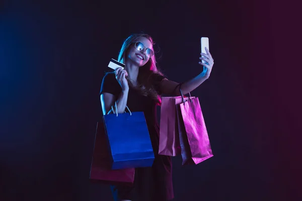 Portret van een jonge vrouw in neonlicht op een donkere rug. De menselijke emoties, zwarte vrijdag, cyber maandag, aankopen, verkoop, financiën concept. — Stockfoto