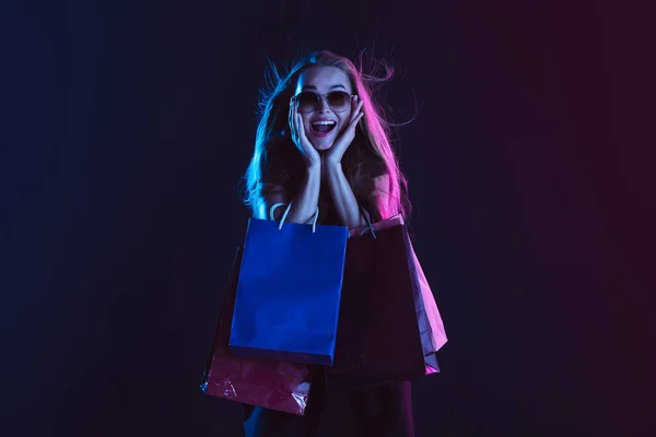 Retrato de mujer joven en luz de neón sobre fondo oscuro. Las emociones humanas, viernes negro, lunes cibernético, compras, ventas, concepto de finanzas. — Foto de Stock