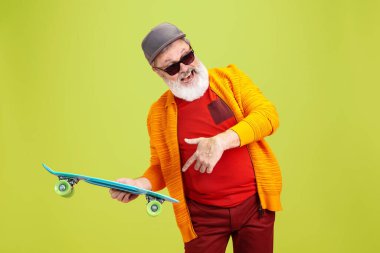 Yeşil arka planda poz veren gözlüklü kıdemli hippi. Teknolojik ve neşeli yaşlı yaşam tarzı konsepti