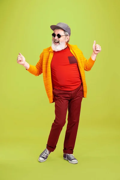 Senior hipster man met een bril die poseert op een groene achtergrond. Technisch en vrolijk ouderenlevensstijl concept — Stockfoto