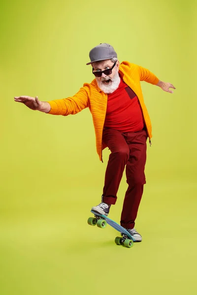 Senior hipster man wearing eyeglasses posing on green background. Tech and joyful elderly lifestyle concept — Stock Photo, Image