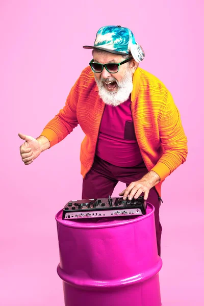 Uomo anziano hipster indossa occhiali in posa su sfondo rosa. Tecnologia e gioioso stile di vita anziano concetto — Foto Stock