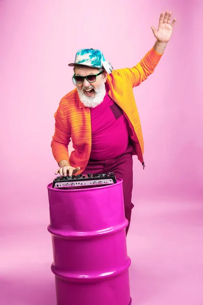 Старший хипстер в очках позирует на розовом фоне. Технология и радостный образ жизни пожилых людей — стоковое фото