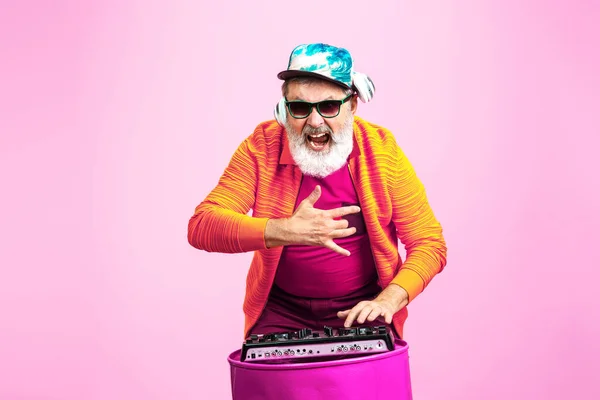 Senior hipster man wearing eyeglasses posing on pink background. Tech and joyful elderly lifestyle concept — Stock Photo, Image