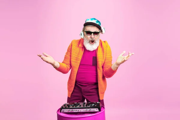 Végzős hipszter férfi szemüvegben, rózsaszín háttéren pózol. Technikai és örömteli időskori életmód koncepció — Stock Fotó