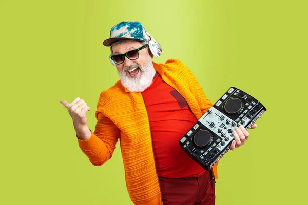 Senior hipster man met een bril die poseert op een groene achtergrond. Technisch en vrolijk ouderenlevensstijl concept — Stockfoto