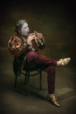 Young man as Johann Sebastian Bach on dark green background. Retro style, comparison of eras concept.