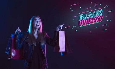 Karanlık arka planda neon ışıklı genç bir kadının portresi. İnsan duyguları, Kara Cuma, siber pazartesi, alışverişler, satışlar, finans konsepti. Neoned harfleri..