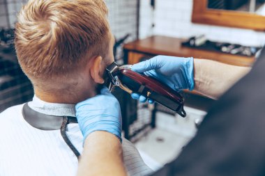 Coronavirus salgını sırasında maske takan bir adam berber dükkanında saçını kestiriyor.