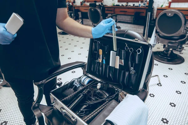 Mannelijke kapper in de kapperszaak met handschoenen ter voorbereiding van de werkplek voor de klant — Stockfoto