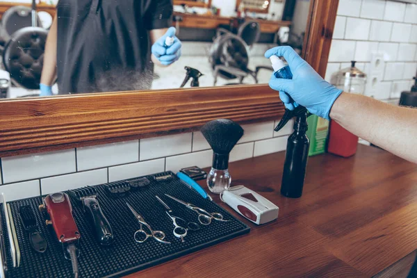 Mannelijke kapper in de kapperszaak met handschoenen ter voorbereiding van de werkplek voor de klant — Stockfoto