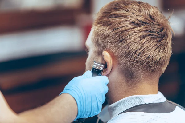 Hombre que se corta el pelo en la barbería usando máscara durante la pandemia de coronavirus —  Fotos de Stock